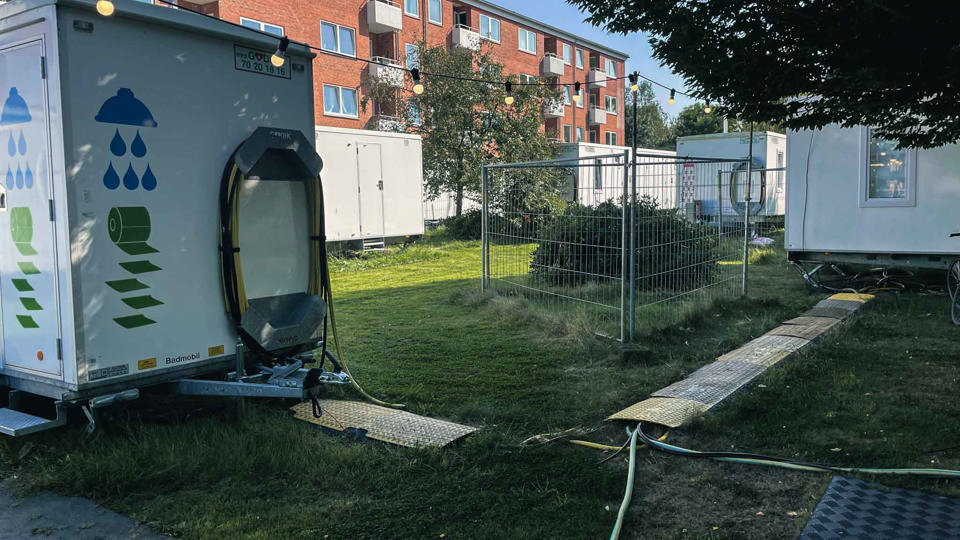 Godik bade- og toiletvogne og beboelsesvogne foran et lejlighedskompleks i forbindelse med renovering og genhusning